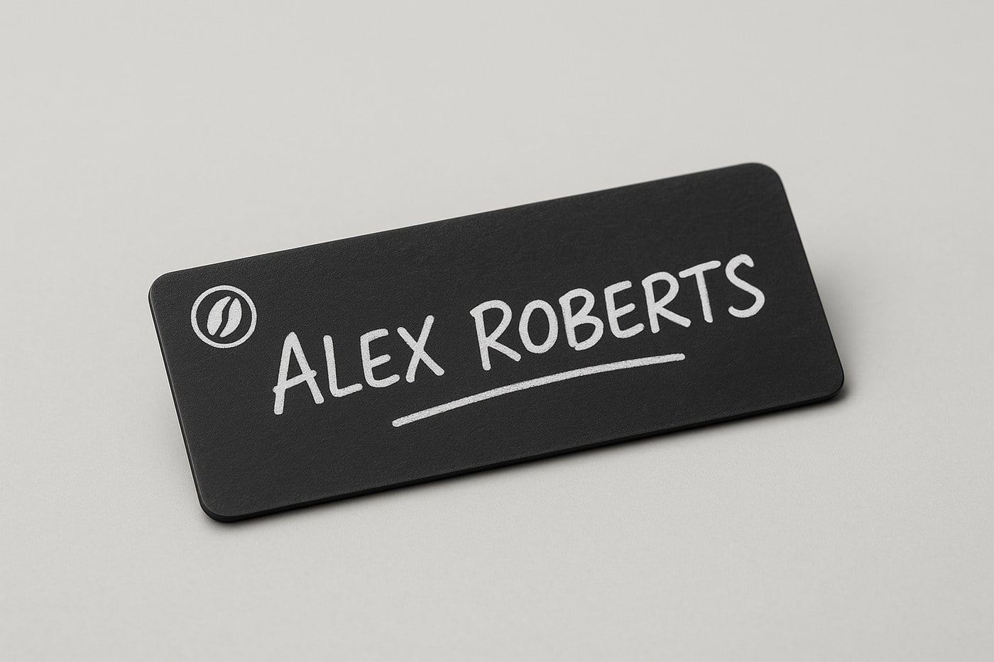 Black chalkboard name badge with a name written in white chalk marker